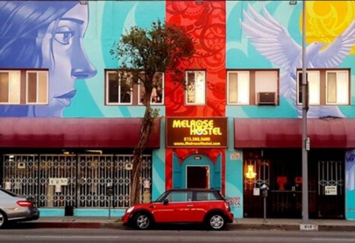 Melrose Hostel Adults Only: Gay-friendly hotel facade with colorful murals, red Mini Cooper parked in front. Great for gay travel in LA.