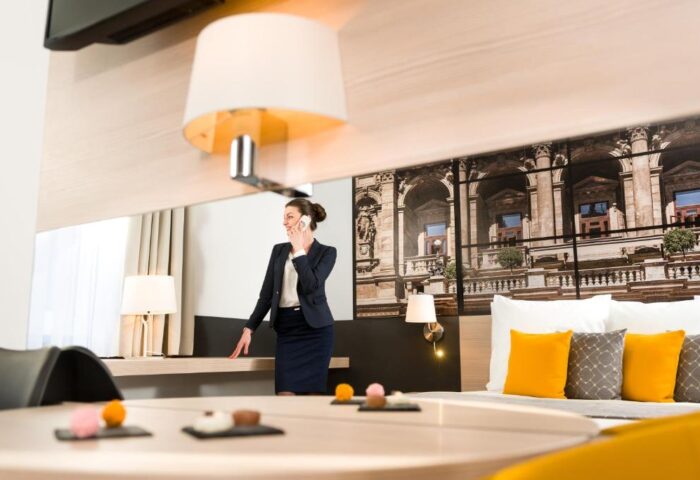 Mercure Budapest City Center Hotel room. Woman on phone. Gay-friendly hotel with modern design, comfy bed, and city view. Perfect for gay travel.