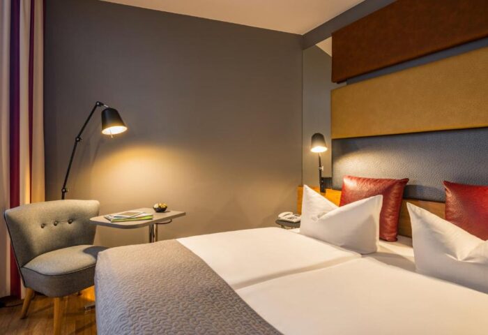 Gay-friendly Mercure Hotel Berlin Zentrum room. Modern design, double bed, chair, and reading lights. Comfortable stay in Berlin.