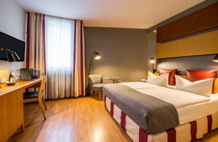 Mercure Hotel Berlin Zentrum room. Gay-friendly hotel with twin beds, desk, chair, and modern decor. Comfortable stay in Berlin's gay district.