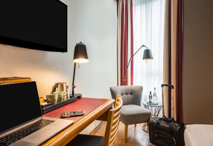 Mercure Hotel Berlin Zentrum room: desk with laptop, chair, & luggage. Gay-friendly hotel for gay men travelers in Berlin. Modern, comfortable.