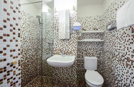 Gay-Friendly Mercure Hotel Berlin Zentrum bathroom. Shower, sink, & toilet with brown & white mosaic tiles. Modern, clean design.