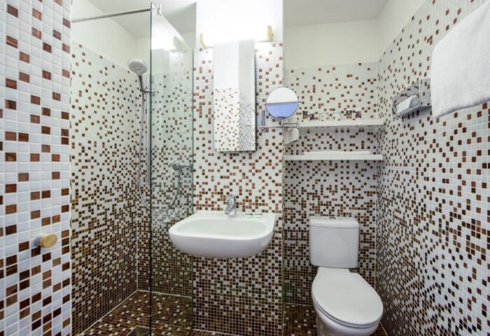 Gay-Friendly Mercure Hotel Berlin Zentrum bathroom. Shower, sink, & toilet with brown & white mosaic tiles. Modern, clean design.