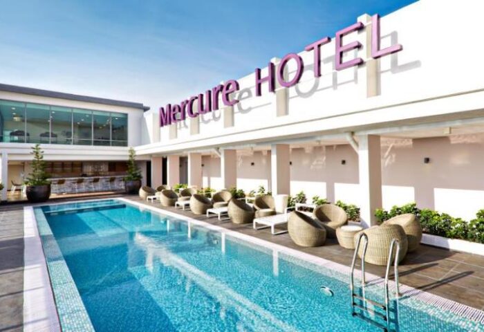 Mercure Kuala Lumpur Shaw Parade, a gay-friendly hotel. Poolside view with lounge chairs and the hotel's sign. Great for gay travelers.