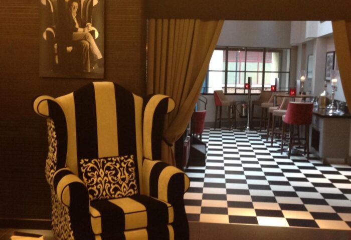 Interior of the gay-friendly Mercure London Bridge Hotel. Black and white striped armchair, checkered floor, and bar area. Stylish design.