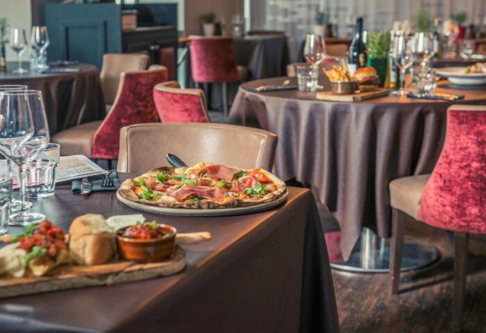 Mercure London Bridge gay-friendly hotel restaurant. Tables set with pizza, appetizers, drinks. Fine dining experience.