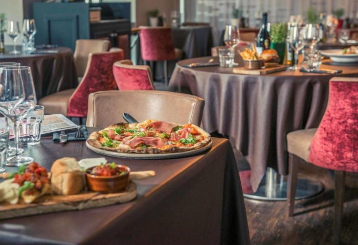 Mercure London Bridge gay-friendly hotel restaurant. Tables set with pizza, appetizers, drinks. Fine dining experience.