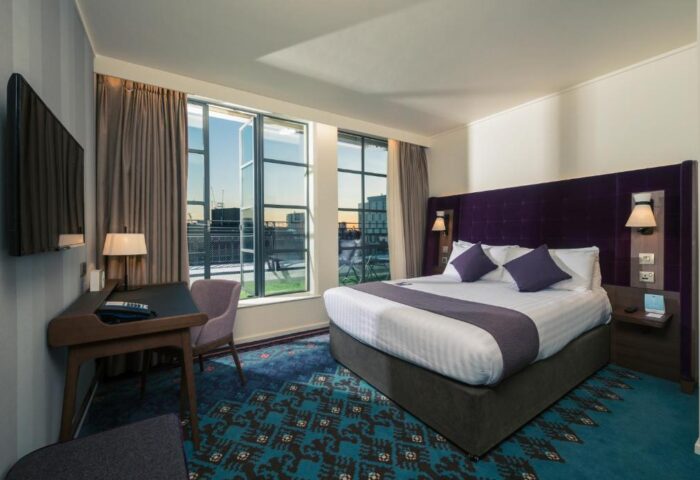Mercure London Bridge gay-friendly hotel room. Modern design with large windows, purple accents, desk, and patterned carpet. Comfortable stay.