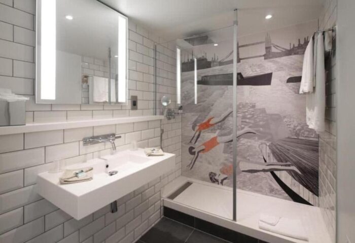Mercure London Bridge gay-friendly hotel bathroom. Shower with London themed graphic. Modern sink, mirror and white subway tile.