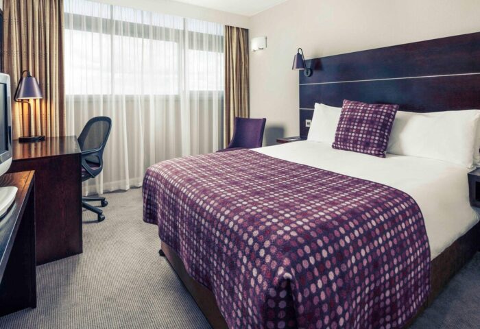 Gay-friendly Mercure Manchester Piccadilly Hotel room. Desk, chair, and bed with purple accents. A great choice for gay men traveling.