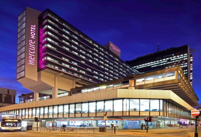 Mercure Manchester Piccadilly Hotel exterior at night. Gay-friendly hotel in Manchester, UK. Modern architecture, street view.