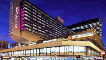 Mercure Manchester Piccadilly Hotel exterior at night. Gay-friendly hotel in Manchester, UK. Modern architecture, street view.