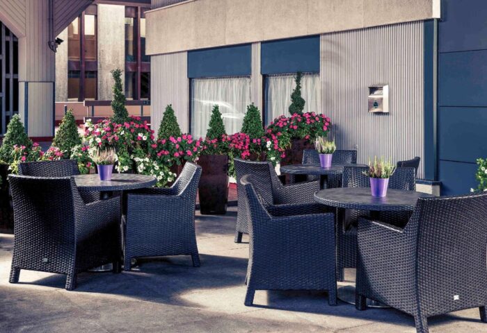 Mercure Manchester Piccadilly Hotel's outdoor seating area. Gay-friendly hotel with tables, chairs, and flowers. Ideal for relaxing.