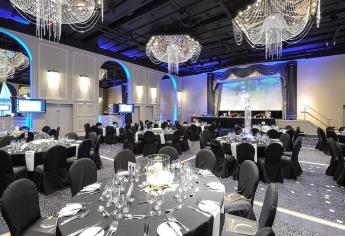 Mercure Manchester Piccadilly Hotel ballroom. Gay-friendly hotel event space with chandeliers, round tables, and stage. Elegant design.