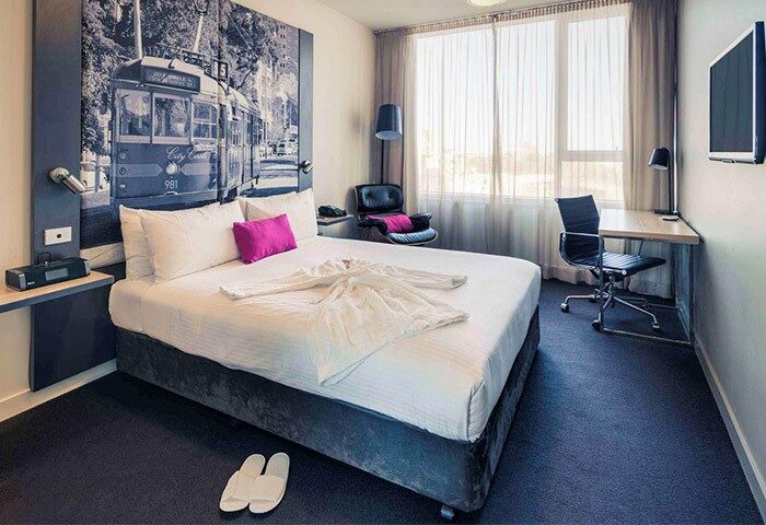 Mercure Melbourne Therry Street hotel room. Gay-friendly hotel with bed, desk, chair, and tram mural. Melbourne travel for gay men.