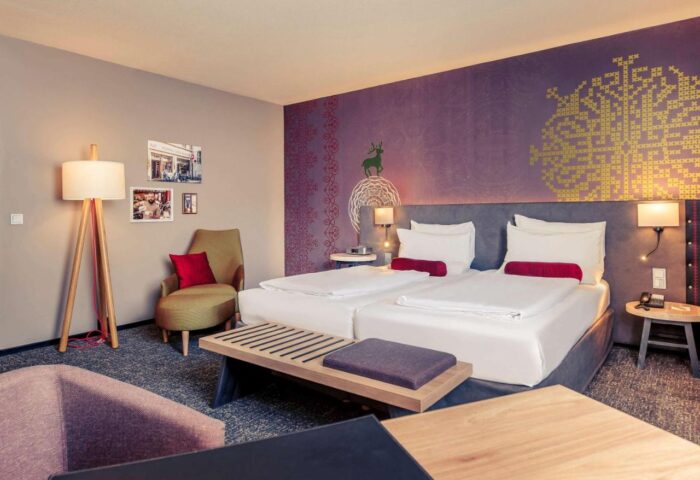 Mercure Munich City Center Hotel room. Gay-friendly hotel with twin beds, modern decor, and cozy seating. Perfect for gay travelers.