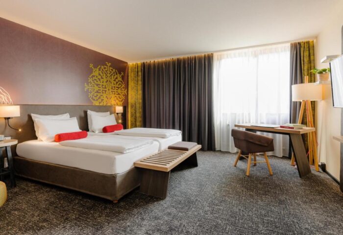 Mercure Munich City Center Hotel room. Twin beds, desk, chair, and modern decor. A gay-friendly hotel for your Munich travel plans.