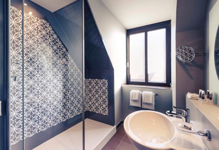 Mercure Munich City Center Hotel bathroom with glass shower featuring geometric design. Gay-friendly hotel for gay men travel in Munich.