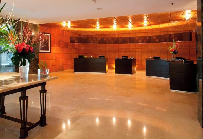 Mexico City Marriott Reforma Hotel lobby. Gay-friendly hotel reception area with desks, floral arrangements, and warm lighting. Mexico travel.