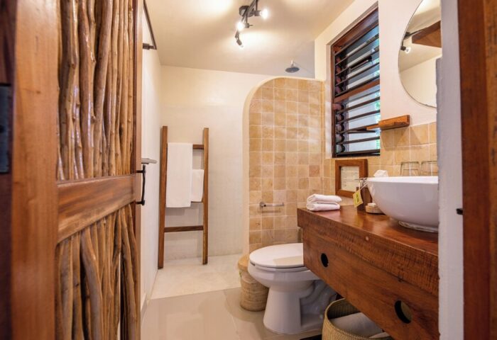 Bathroom at Mezzanine a Colibri Boutique Hotel-Adults Only. Gay-friendly hotel with rustic wood door, tiled shower, and modern sink.