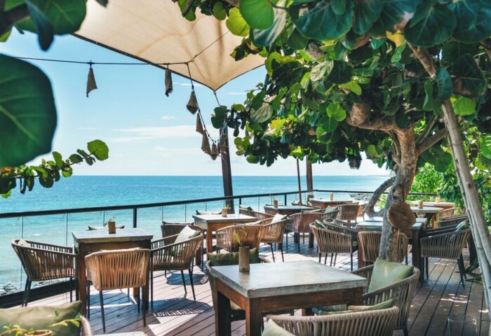 Outdoor dining at Mezzanine a Colibri Boutique Hotel, adults only, gay-friendly hotel. Ocean view, tables and chairs on a wooden deck.
