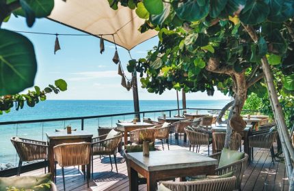 Outdoor dining at Mezzanine a Colibri Boutique Hotel, adults only, gay-friendly hotel. Ocean view, tables and chairs on a wooden deck.