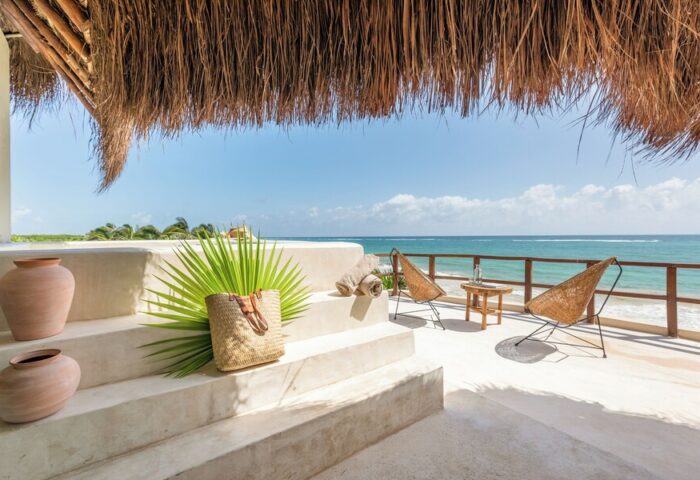 Ocean view from Mezzanine a Colibri Boutique Hotel-Adults Only, a gay-friendly hotel. Chairs, beach bag, and thatched roof.