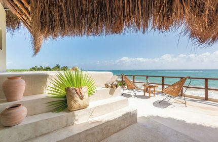 Ocean view from Mezzanine a Colibri Boutique Hotel-Adults Only, a gay-friendly hotel. Chairs, beach bag, and thatched roof.