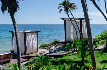 Mi Amor a Colibri Boutique Hotel adults-only. Beach cabanas at gay-friendly hotel in Tulum, Mexico. Ocean view with palm trees.
