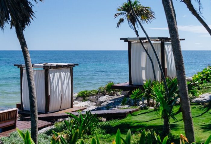 Mi Amor a Colibri Boutique Hotel adults-only. Beach cabanas at gay-friendly hotel in Tulum, Mexico. Ocean view with palm trees.