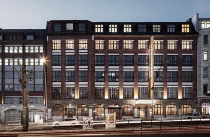 Michelberger Hotel facade at dusk. Gay-friendly hotel in Berlin, Germany. Brick building with illuminated windows. Travel advice for gay men.