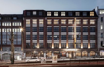Michelberger Hotel facade at dusk. Gay-friendly hotel in Berlin, Germany. Brick building with illuminated windows. Travel advice for gay men.