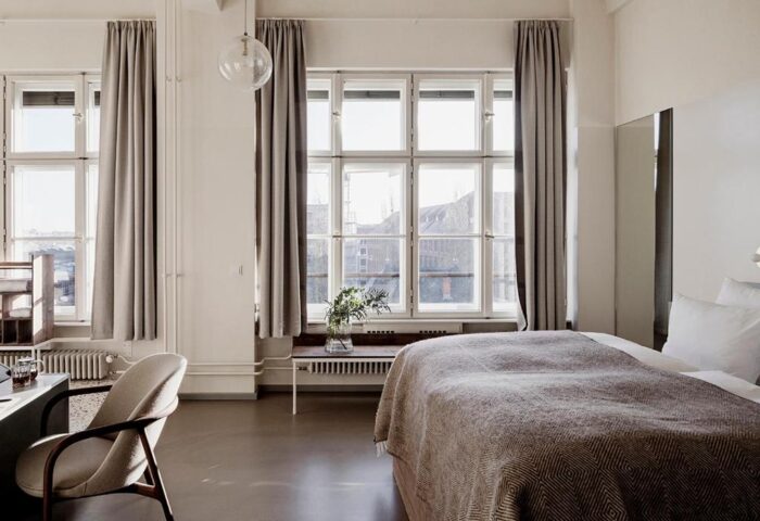 Michelberger Hotel room. Gay-friendly hotel with a bed, large window, curtains, desk, and chair. Modern design, perfect for gay travelers.