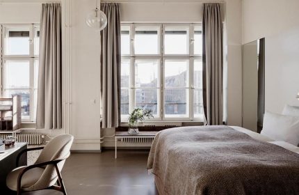 Michelberger Hotel room. Gay-friendly hotel with a bed, large window, curtains, desk, and chair. Modern design, perfect for gay travelers.