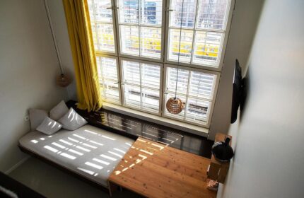 Michelberger Hotel room interior, a gay-friendly hotel. Features a large window, bed, table, and modern decor. Great for gay men travel advice.