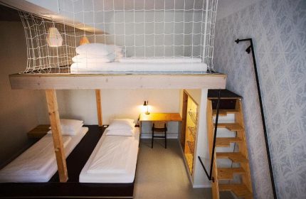 Michelberger Hotel room with bunk beds. Gay-friendly hotel with unique design. Loft bed with safety net, workspace, & stairs. Quirky, stylish decor.