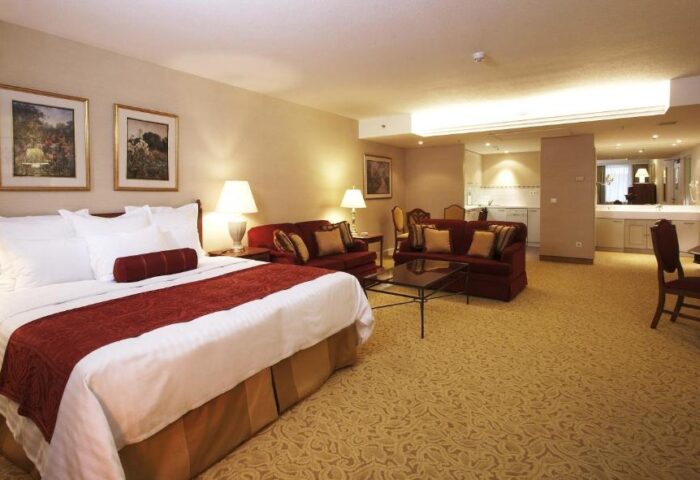 Millennium Court Budapest Marriott Executive Apartments suite. Gay-friendly hotel room with bed, sofas, kitchen, and dining area.