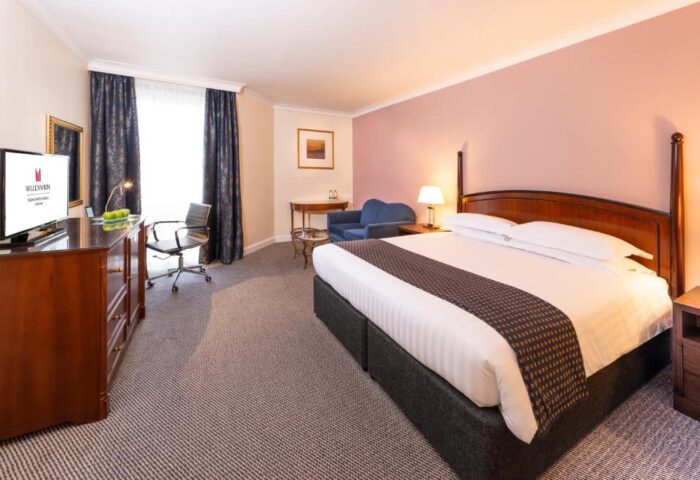 Millennium Gloucester Hotel London bedroom. Gay-friendly hotel with bed, desk, and seating area. Comfortable stay for gay travelers in London.