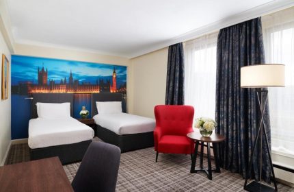 Millennium Gloucester Hotel London room with twin beds, red chair, and London skyline mural. Gay-friendly hotel for gay men travelers.