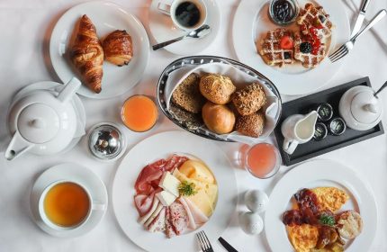 Breakfast spread at Millennium Gloucester Hotel London. Croissants, waffles, meats, cheeses, eggs, juice, coffee, and tea. Gay-friendly hotel.