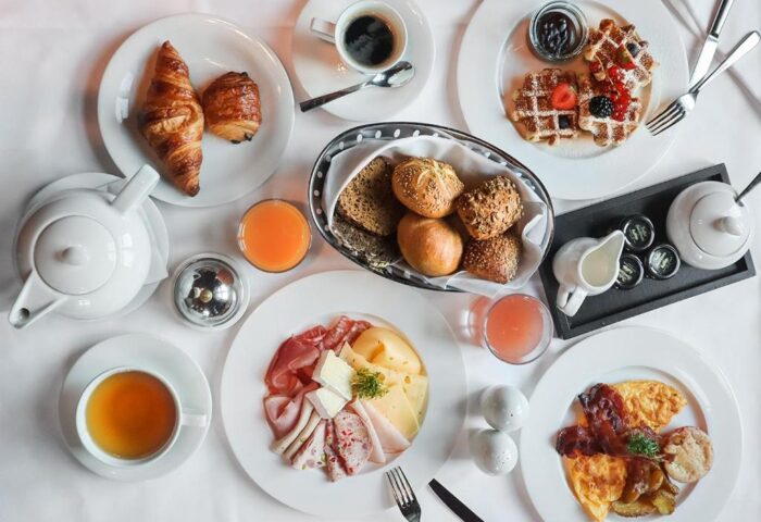 Breakfast spread at Millennium Gloucester Hotel London. Croissants, waffles, meats, cheeses, eggs, juice, coffee, and tea. Gay-friendly hotel.