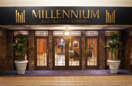 Millennium Gloucester Hotel London's entrance. This gay-friendly hotel features elegant doors, planters, and a welcoming ambiance for gay travelers.