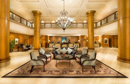 Millennium Gloucester Hotel London lobby. Gay-friendly hotel with elegant seating, chandelier, and reception desk. Ideal for gay travel in London.