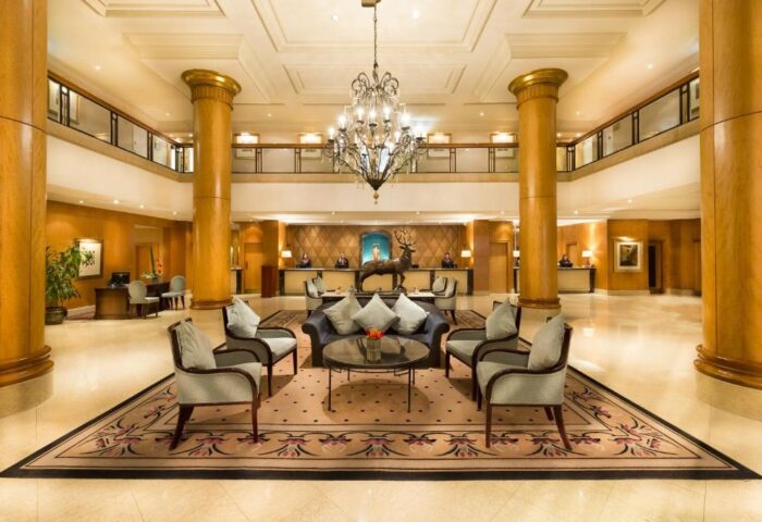 Millennium Gloucester Hotel London lobby. Gay-friendly hotel with elegant seating, chandelier, and reception desk. Ideal for gay travel in London.