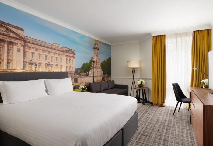 Millennium Gloucester Hotel London: Gay-friendly hotel room with a double bed, desk, sofa, and a mural of Buckingham Palace.
