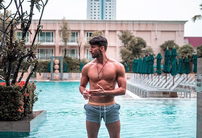 Gay-friendly M Social Hotel Phuket: Muscular man in swim trunks stands in a pool at Millennium Resort Patong, Phuket. Gay travel advice.