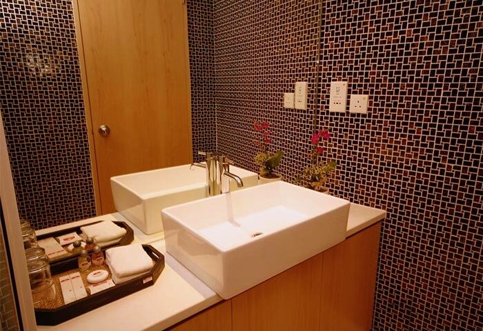 Modern bathroom at Gay-Friendly-Hotel-Mingle-At-The-Eden. Square sinks, mosaic tile wall, and wooden accents create a stylish, clean space.
