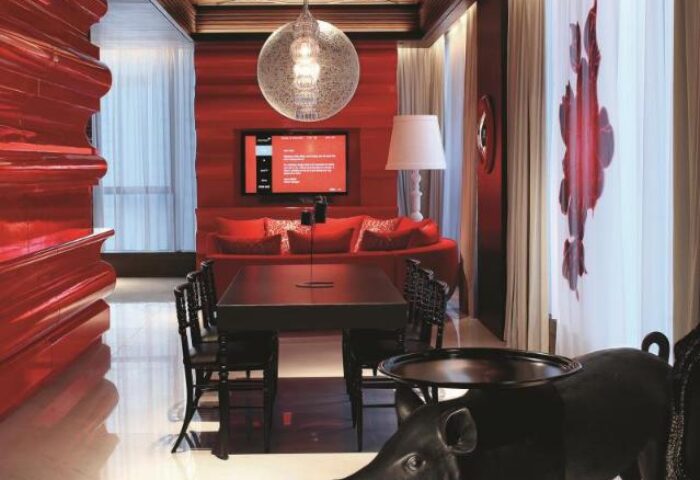 Mira Moon, gay-friendly hotel: Room interior with red walls, modern furniture, pig-shaped table. A stylish stay for gay travelers.