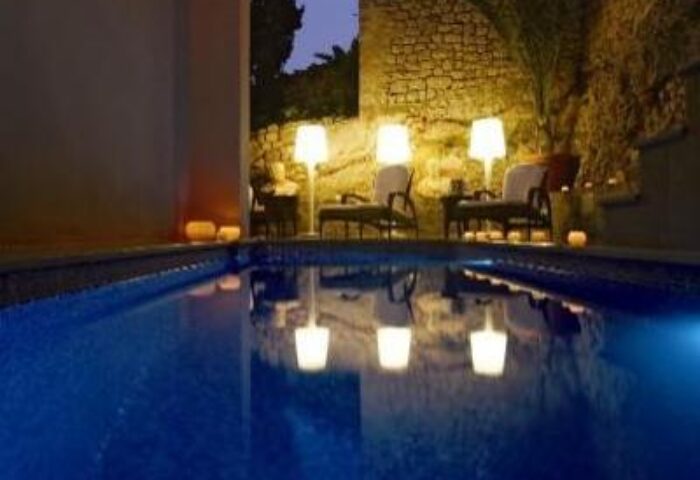 Poolside lounge at Mirador de Dalt Vila-Relais & Chateaux, a gay-friendly hotel. Evening ambiance with illuminated seating area.