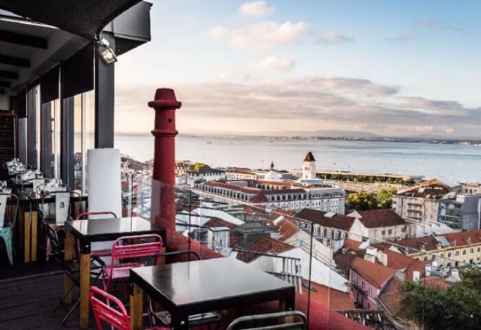 Rooftop view from Monte Belvedere Hotel by Shiadu, a gay-friendly hotel in Lisbon. Tables overlook the city and Tagus River, perfect for gay travel.